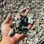 Hand holding a small pile of gray stones with a background of more stones