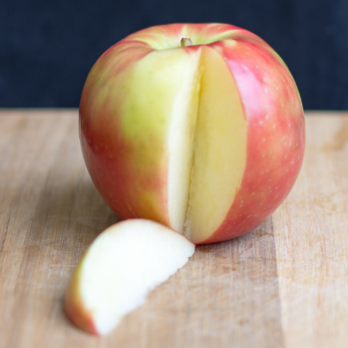 Half-cut Honey Crisp Apple on a wooden surface with a dark background
