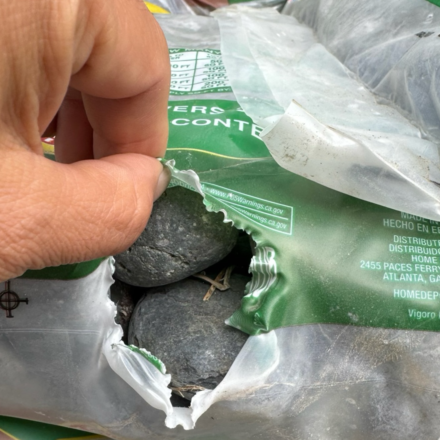 Hand holding a rock above a bag 