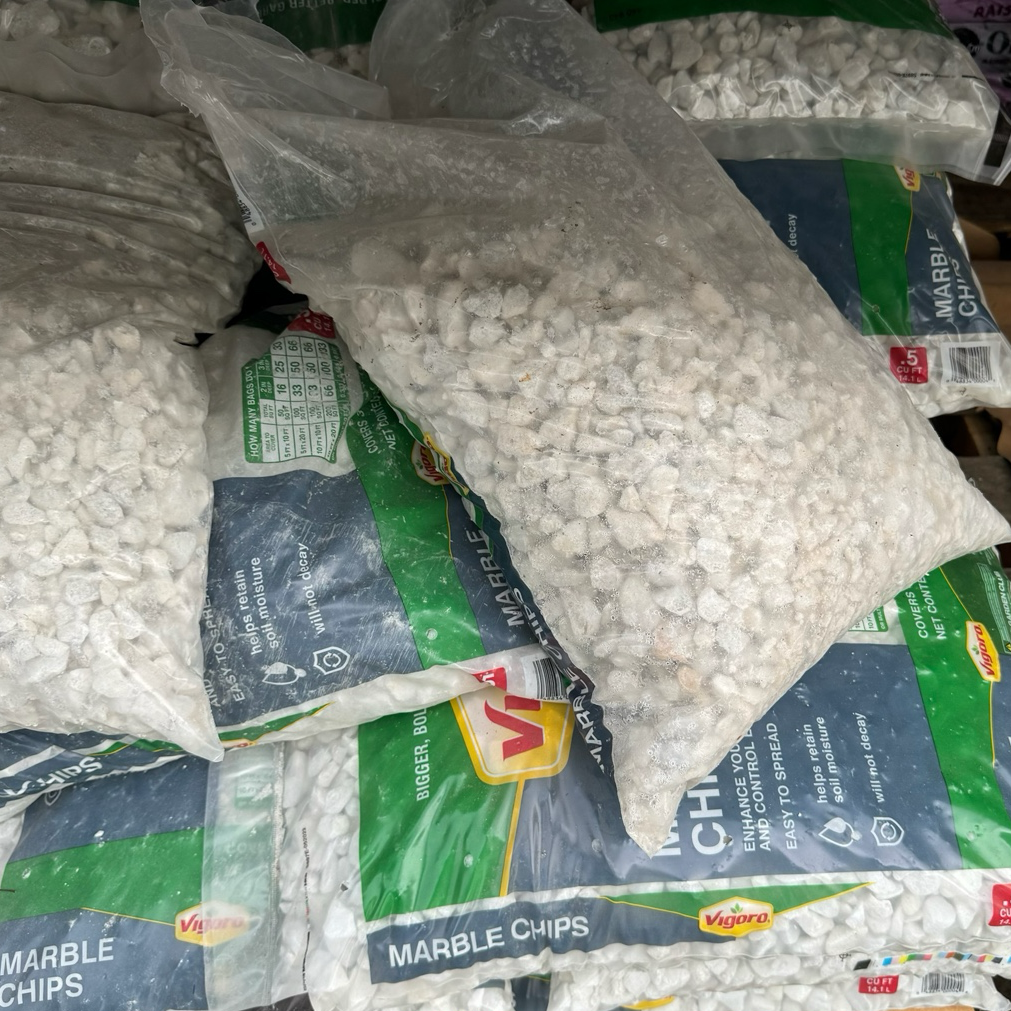 Piles of bags labeled 'Marble Chips' on a wooden pallet.