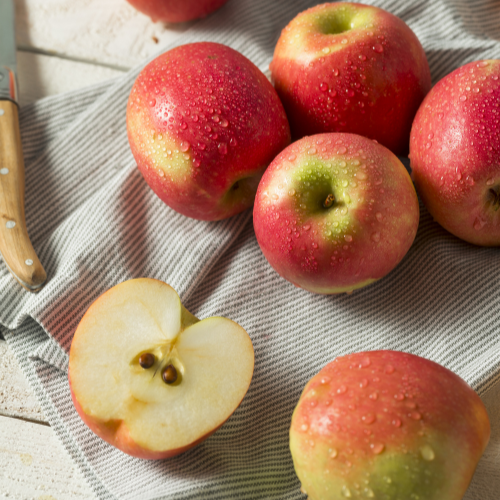 Red Pink Lady Apples with a halved apple on a textured surface