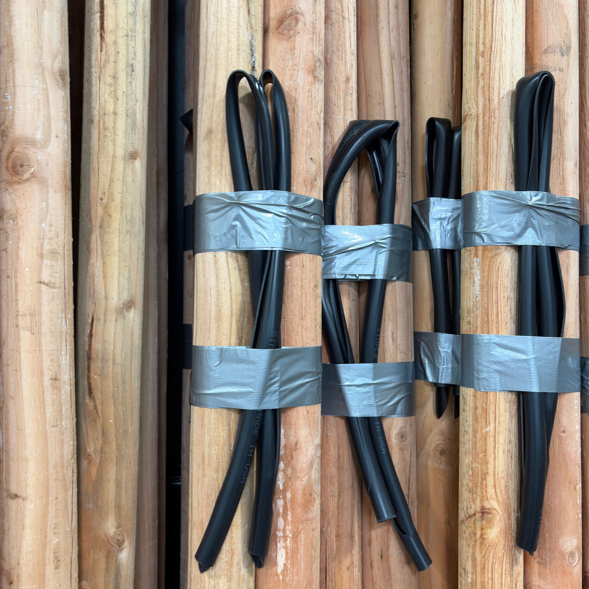 Black cables wrapped with duct tape on a Wood Planting Poles