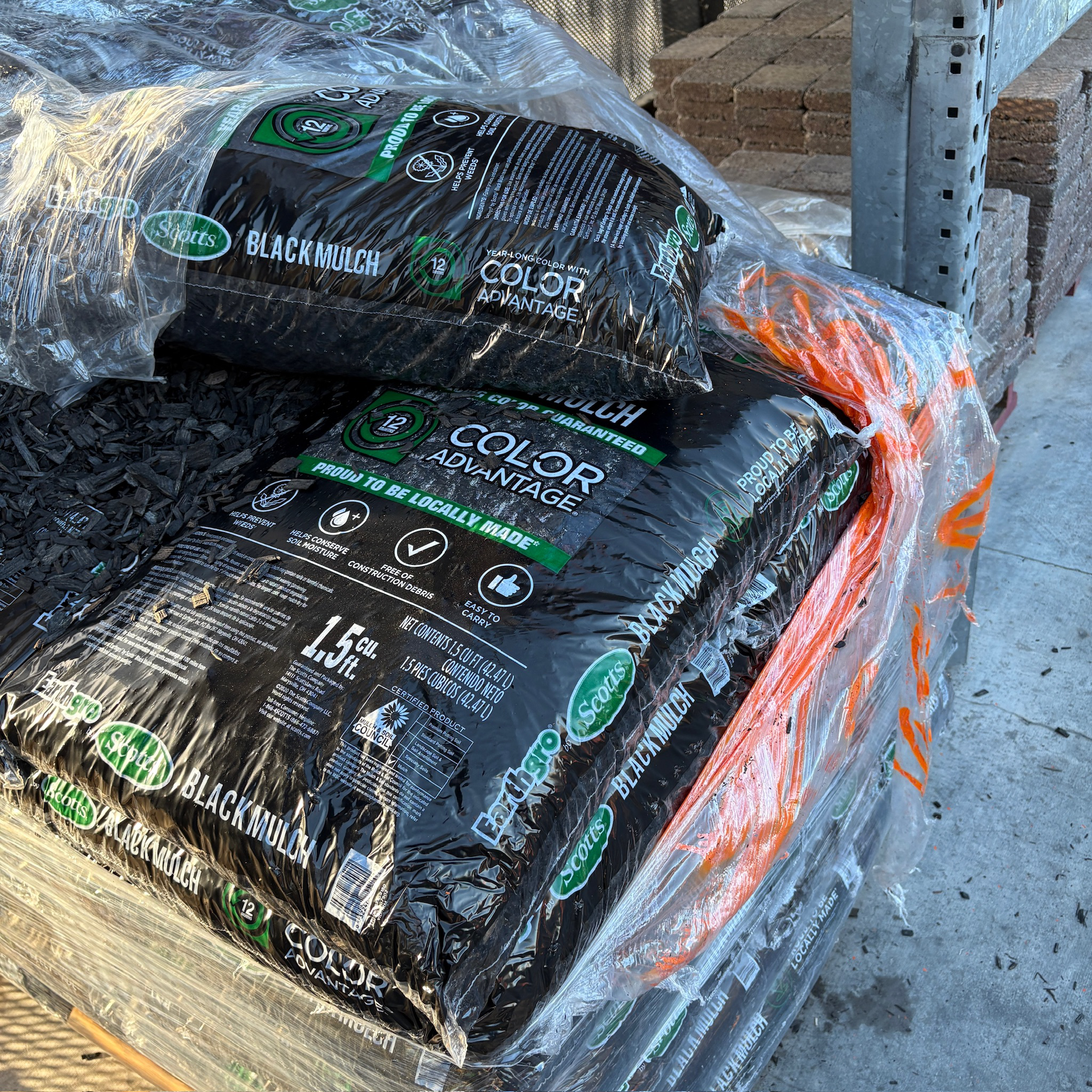Bags of black mulch labeled 'Color Advantage' on a pallet.