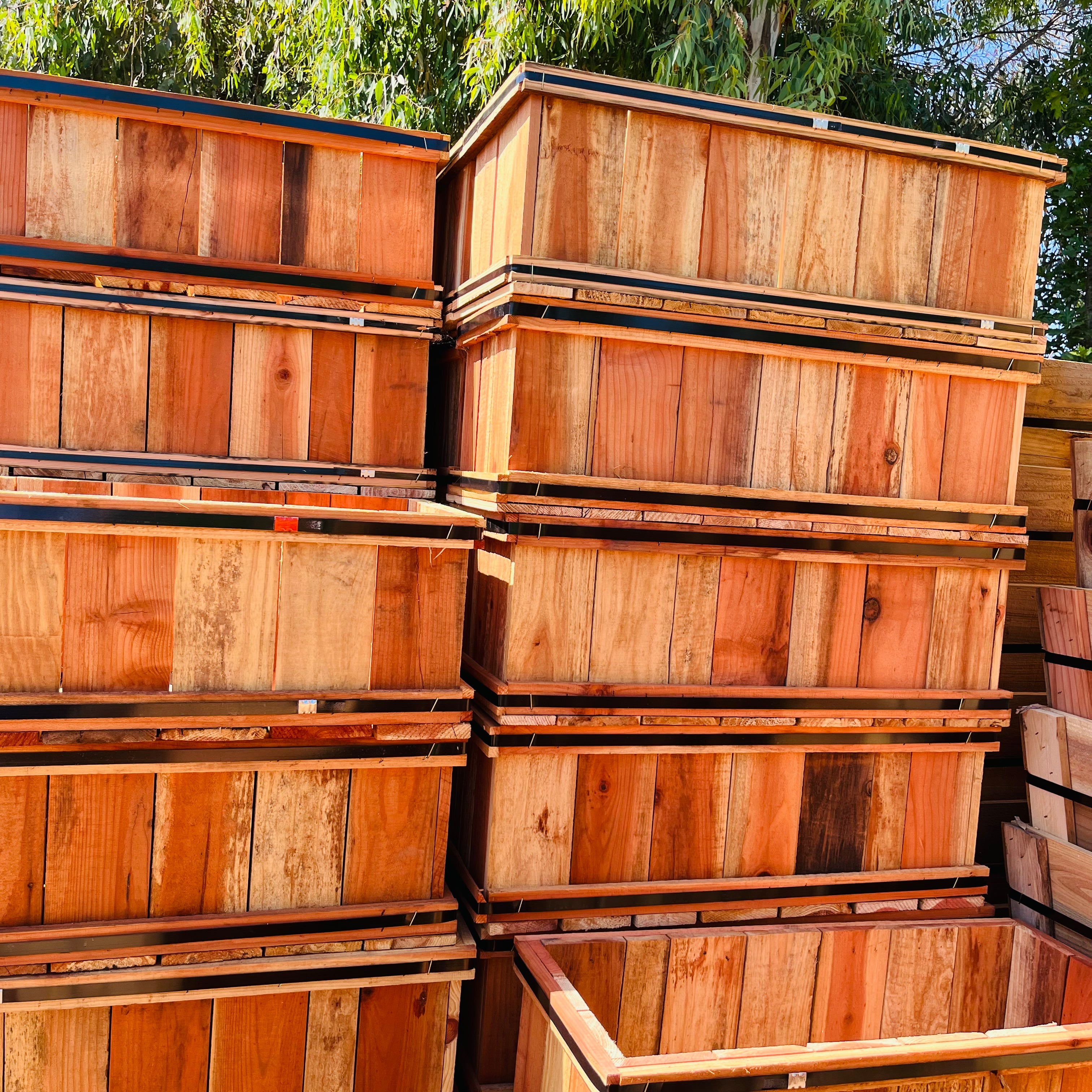Stack of wooden crates outdoors with greenery in the background