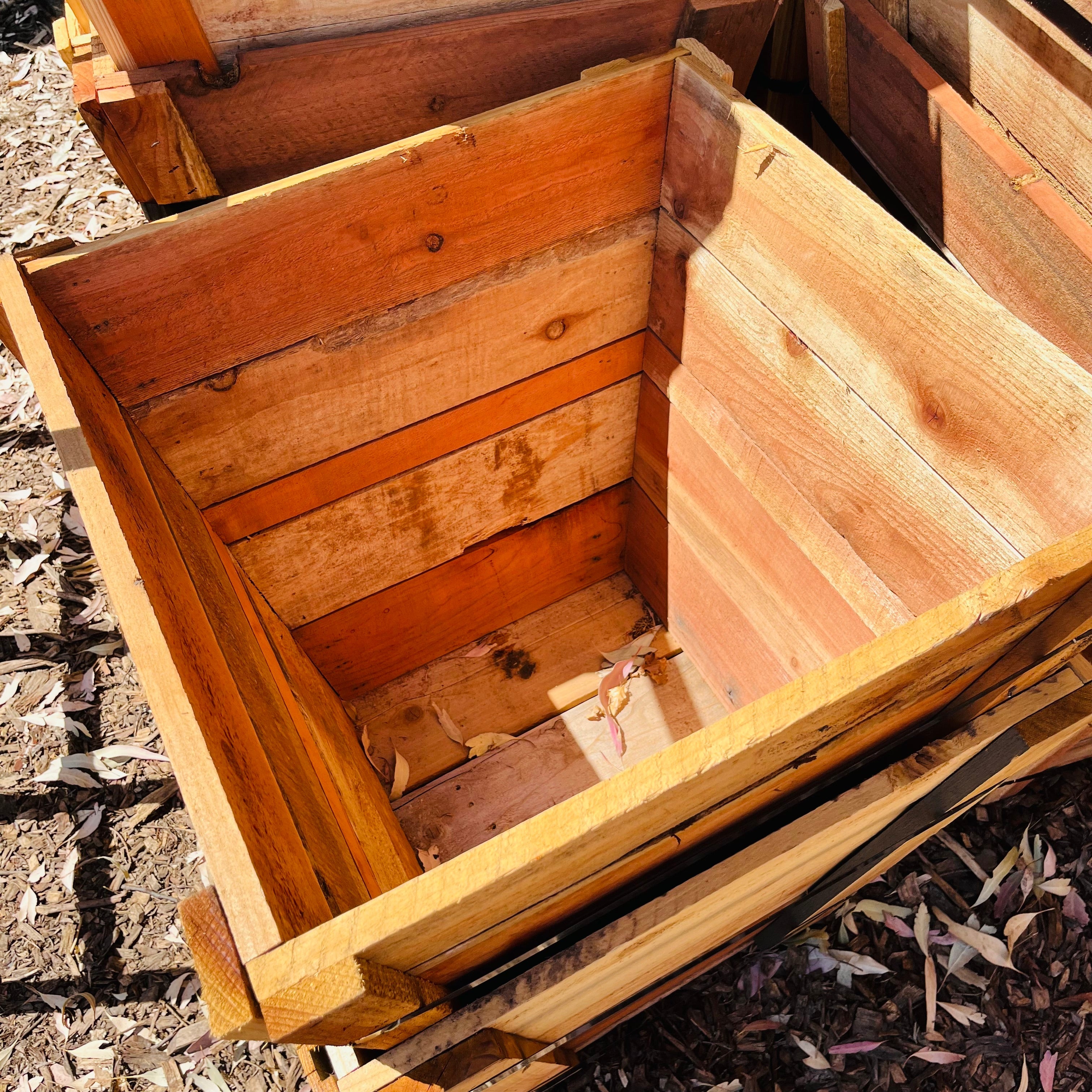 Wooden compost bin with a lid on a mulched surface