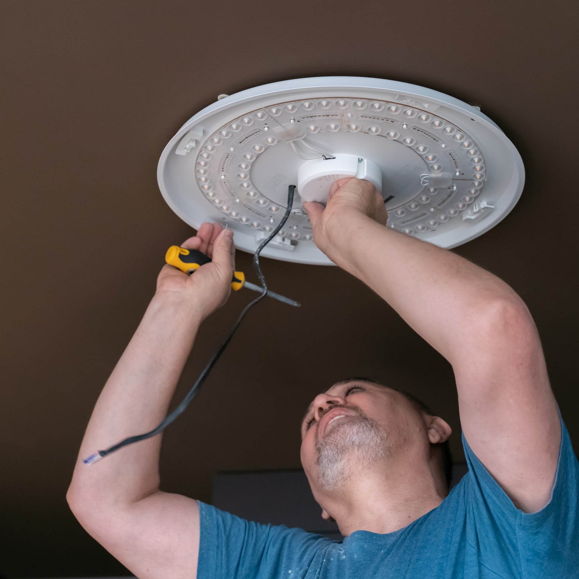 Handyman installing a light fixture on a ceiling